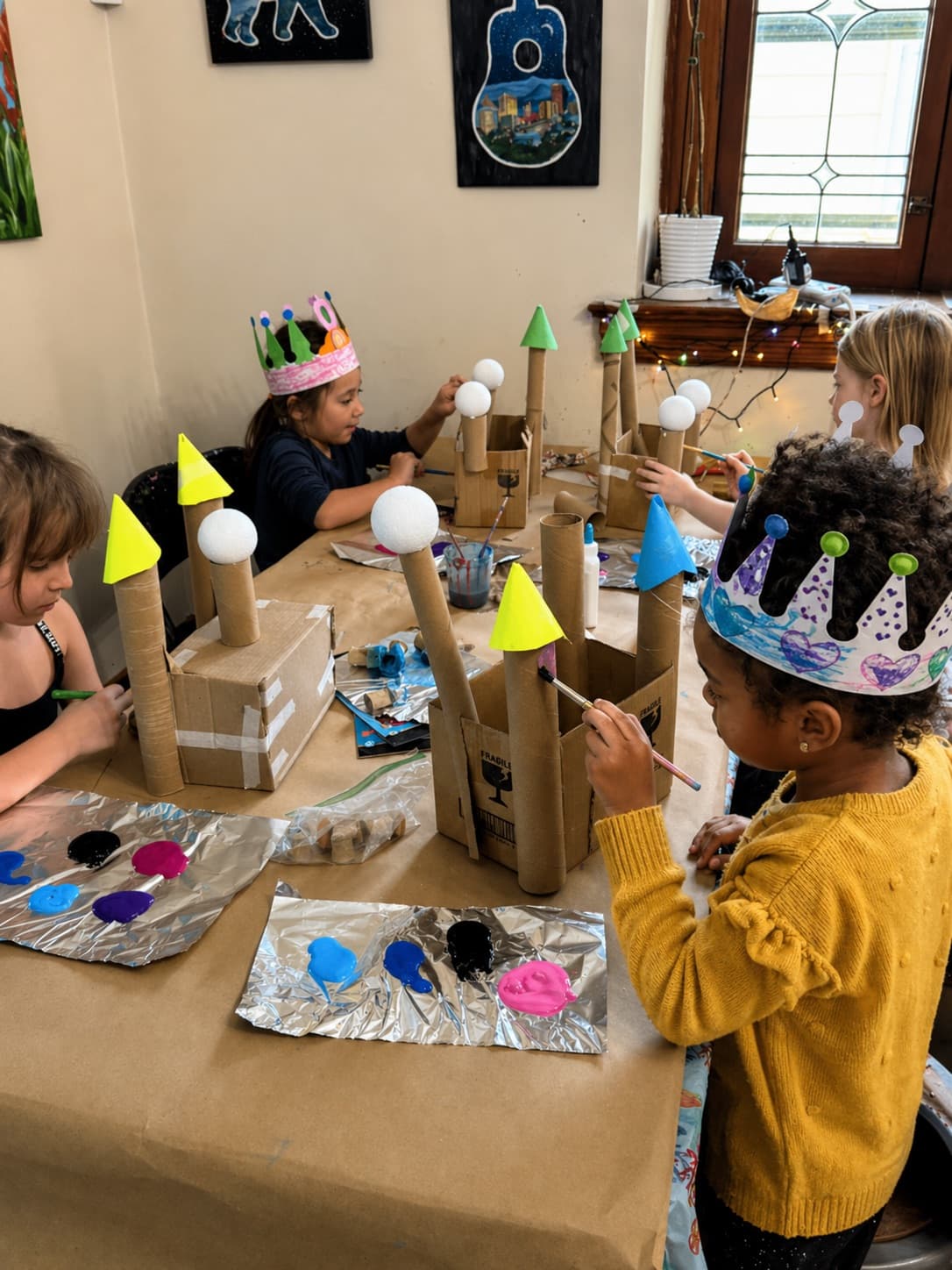 Kids painting cardboard castles together at an art birthday party