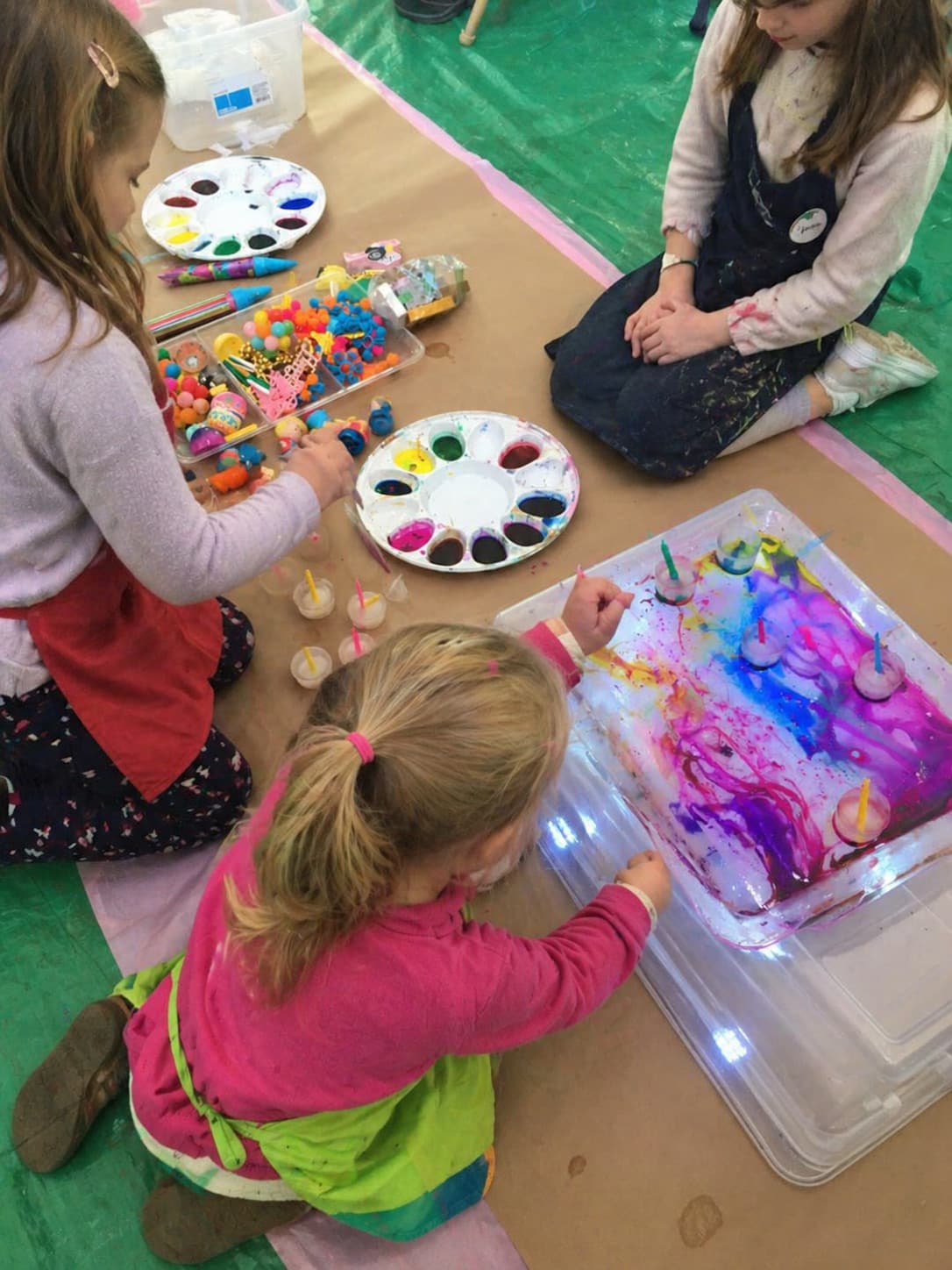 Three small girls exploring a sensory paint tray together