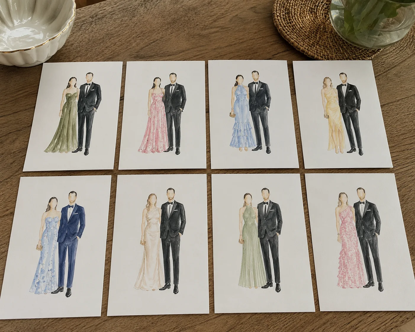 Eight live watercolor guest portraits laid out in a grid on a wooden table, showing couples in green, pink, blue, yellow, and ivory formalwear